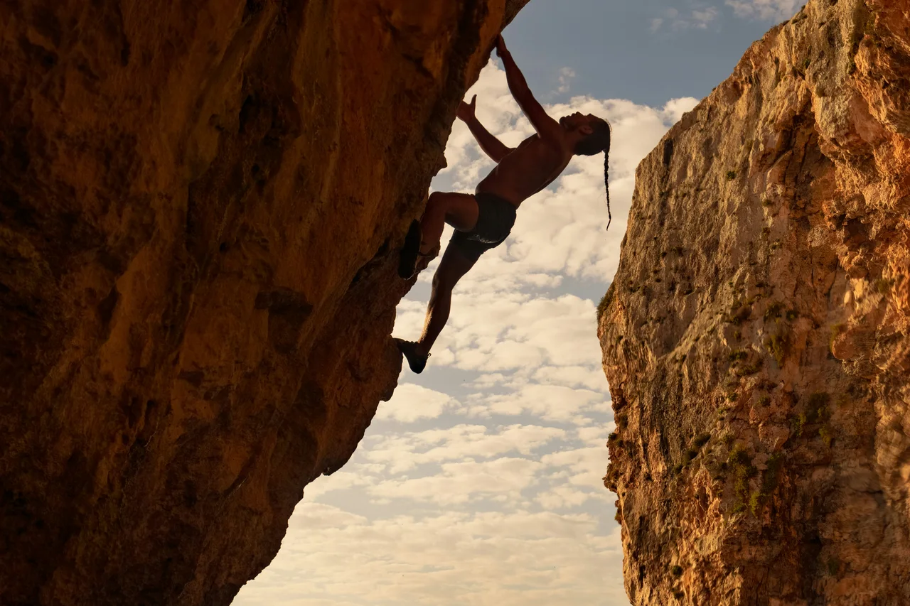 A climber silhouetted against the sky between two rock faces
