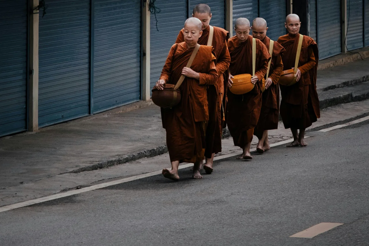 A group of monks walking beside wooden buildings