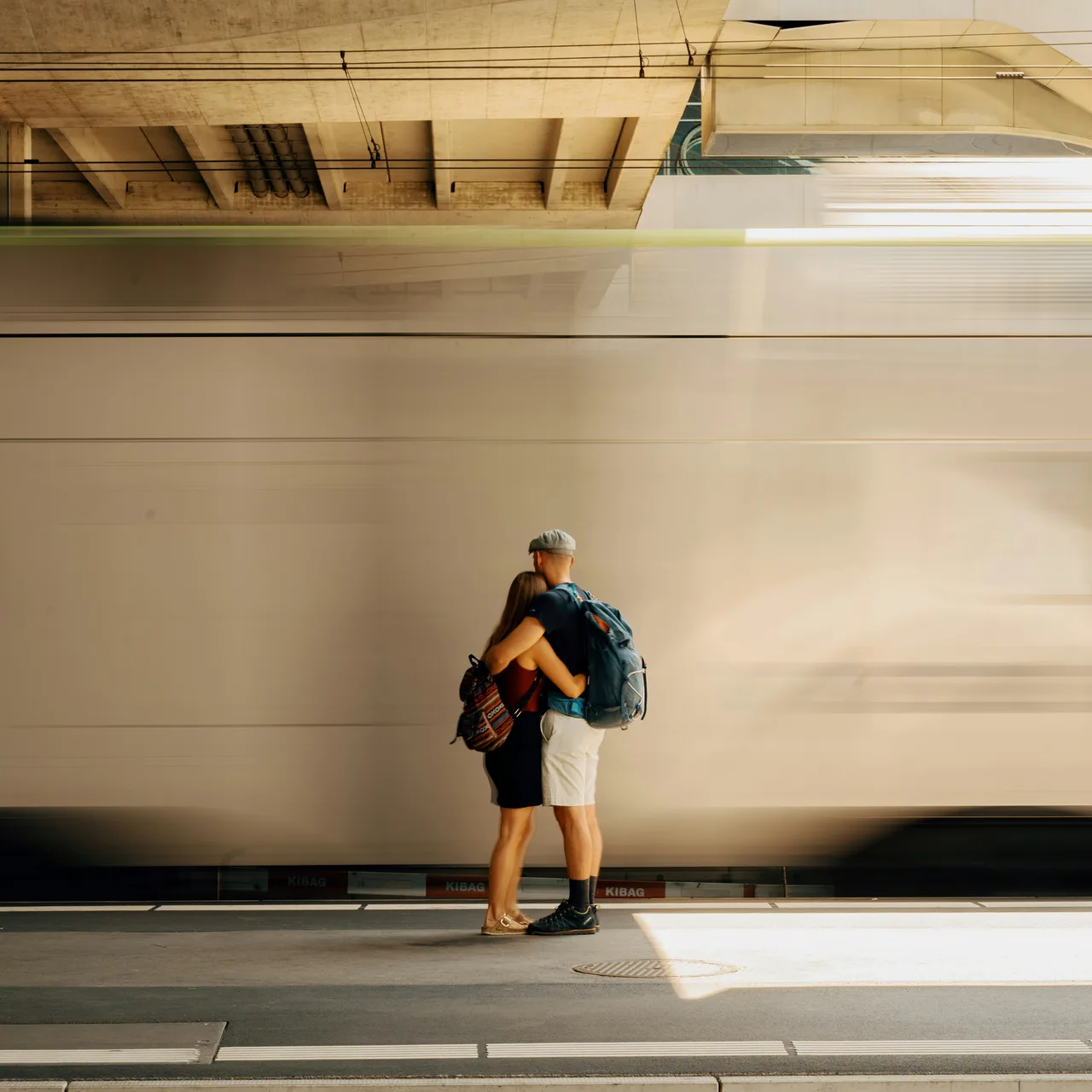 A traveller waiting on a platform beside a passing train