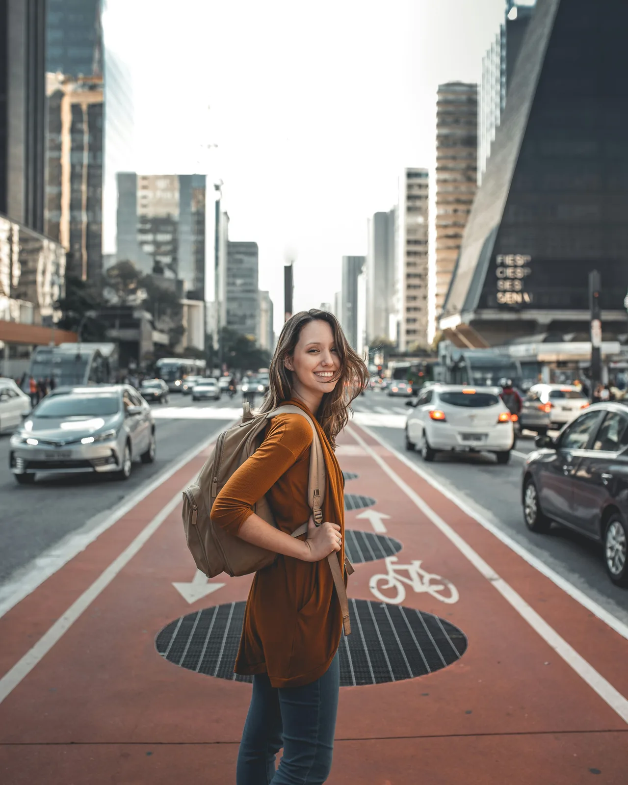 A woman turning toward the camera on a busy city avenue
