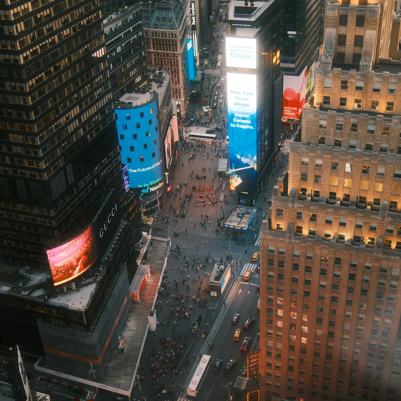 Illuminated billboards and tall city buildings seen from above at dusk