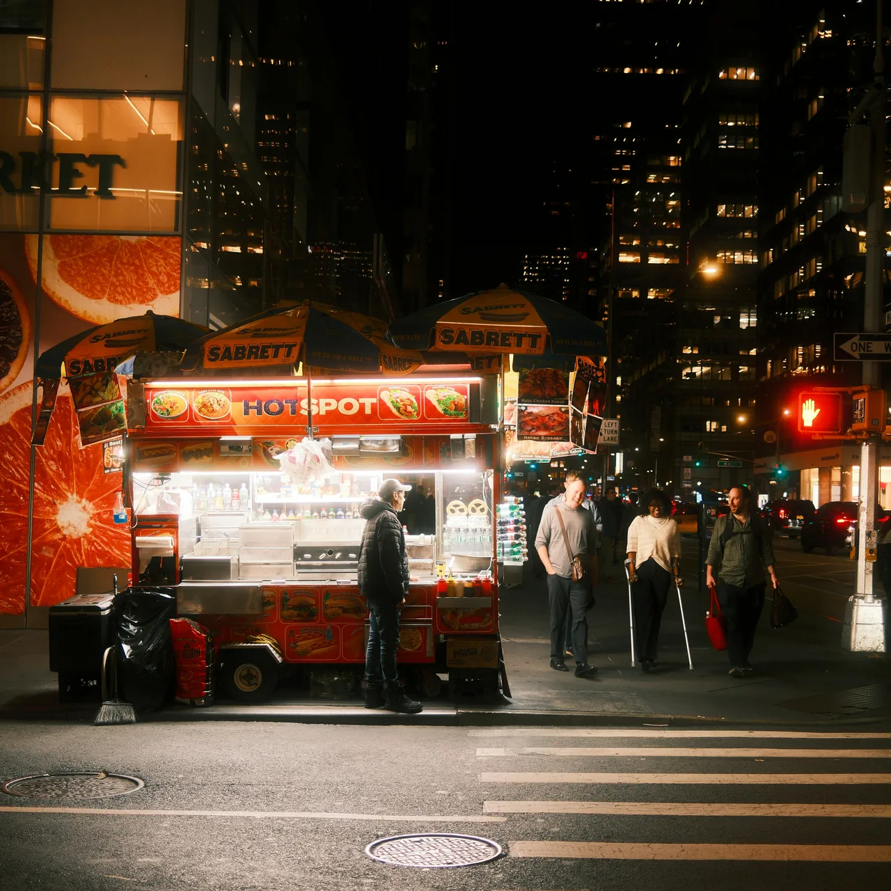 People gathered around a brightly lit food cart on a city street at night