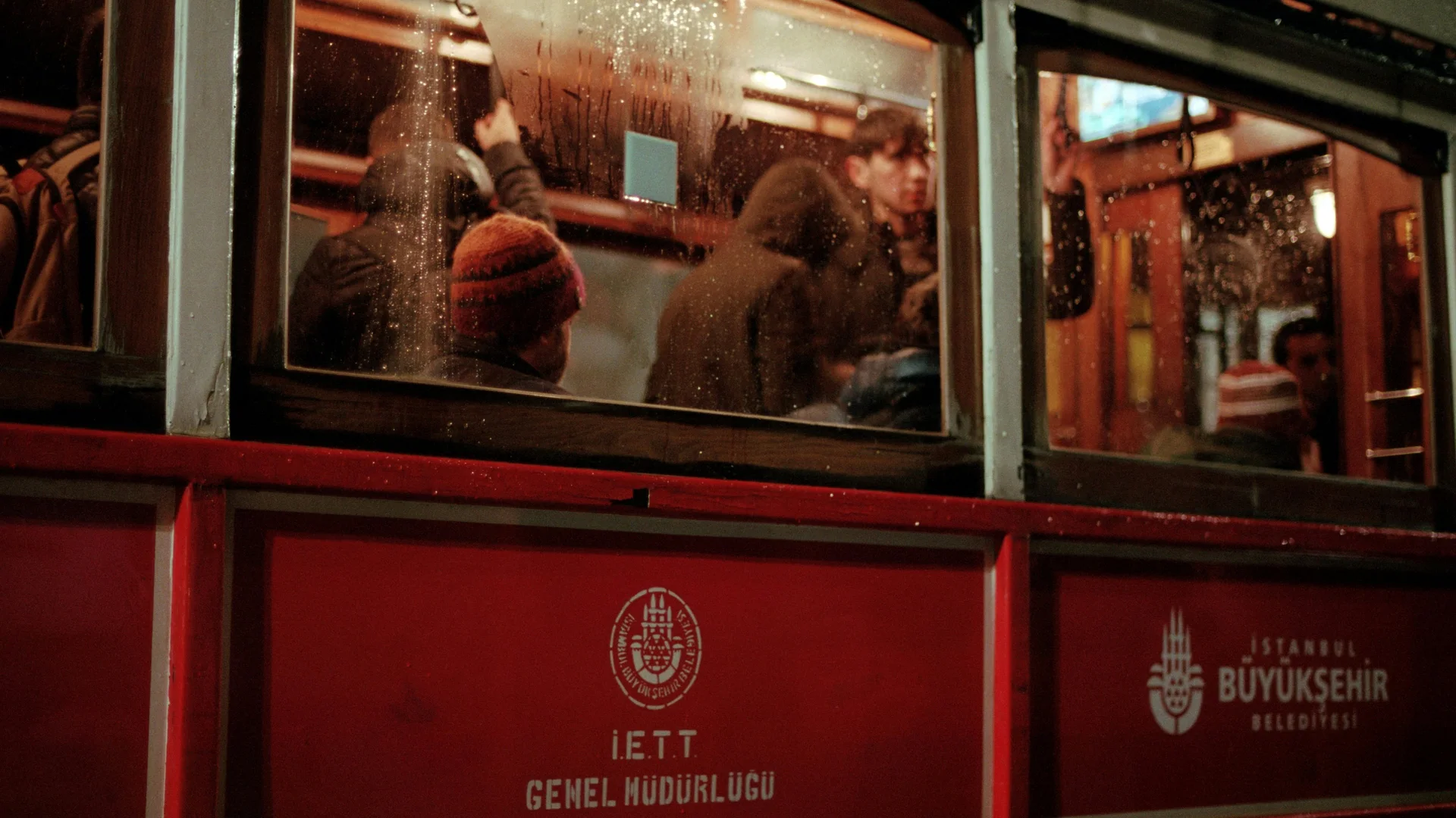 Passengers inside a warmly lit red tram at night