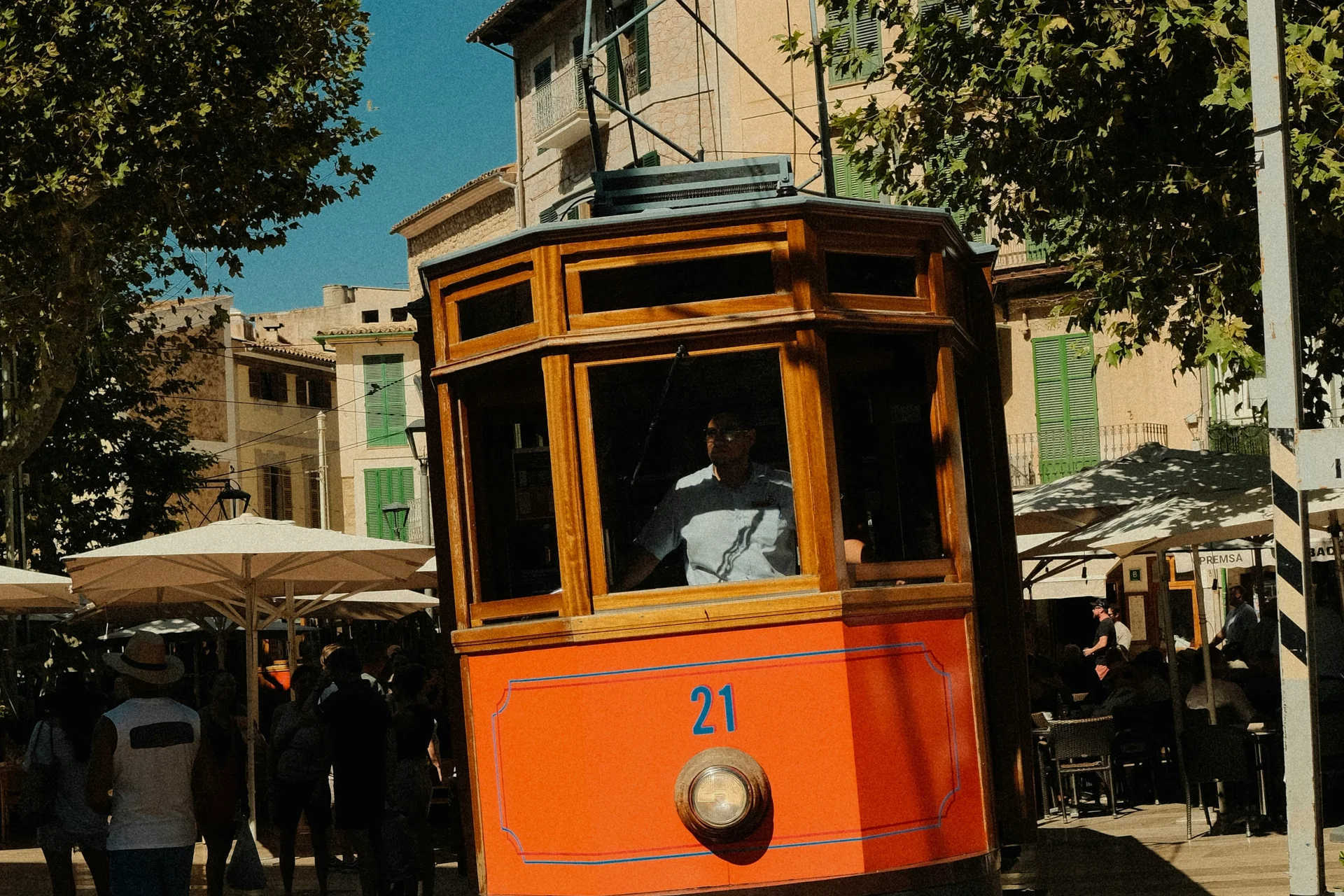 An orange tram on a tree-lined city street