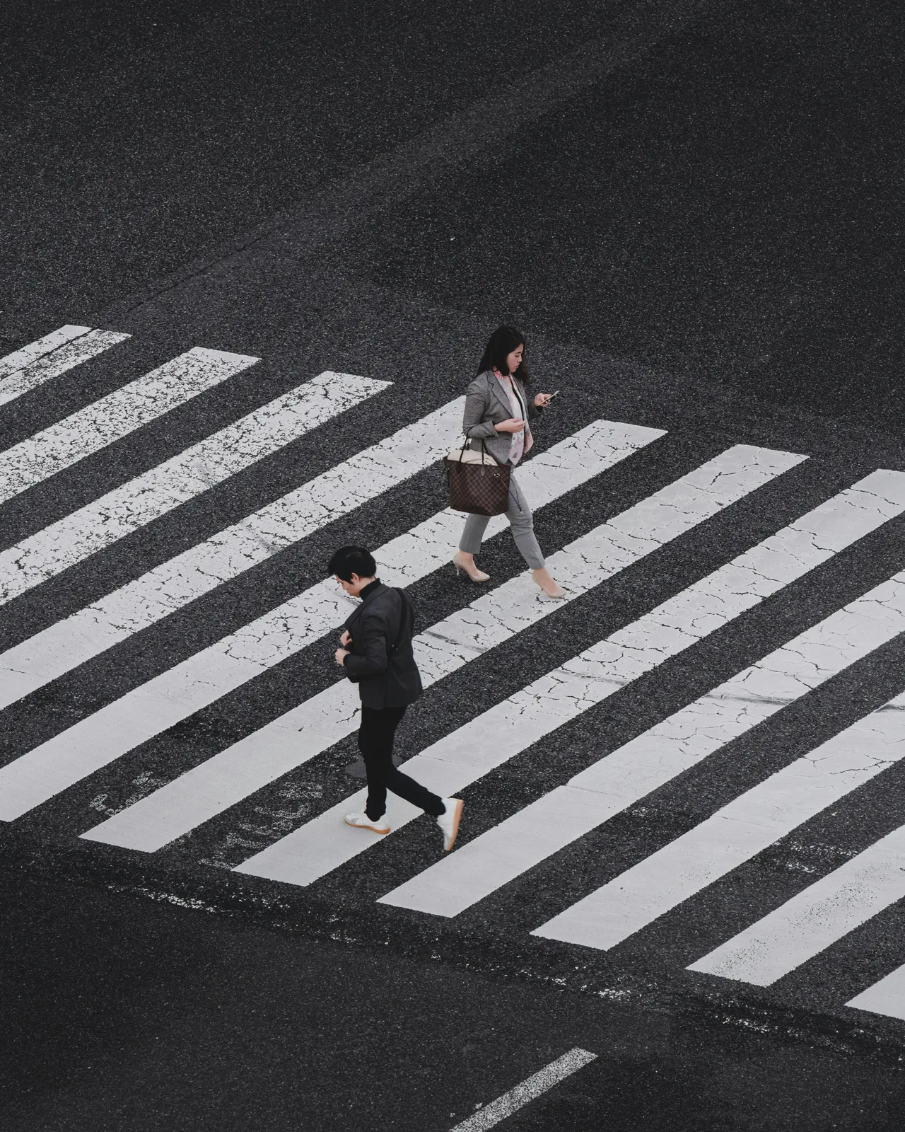 Pedestrians crossing broad white stripes on a city street