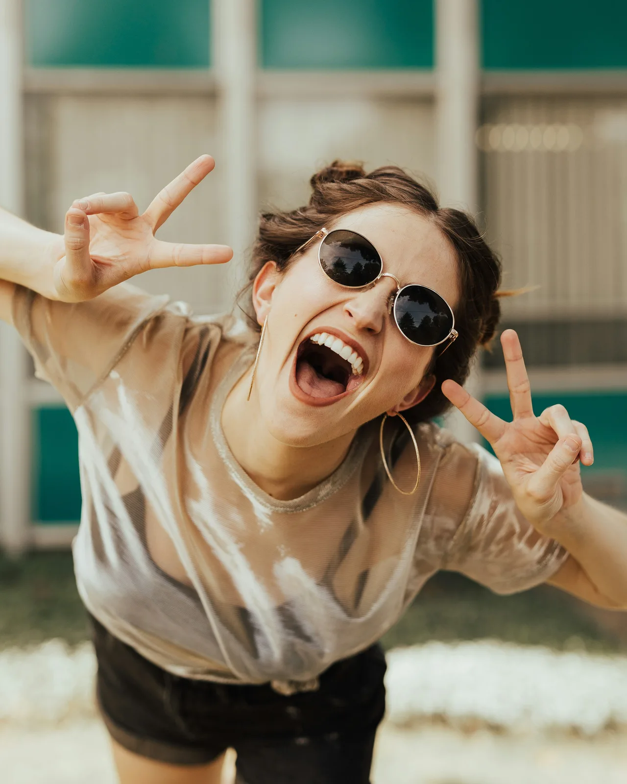 A smiling woman in sunglasses leaning toward the camera