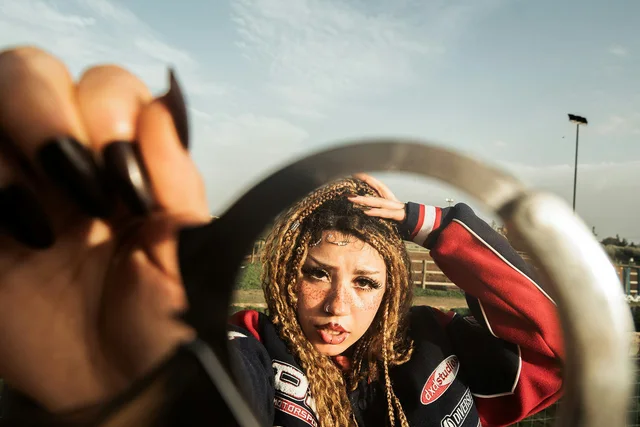 A woman reflected in a round mirror held toward the camera