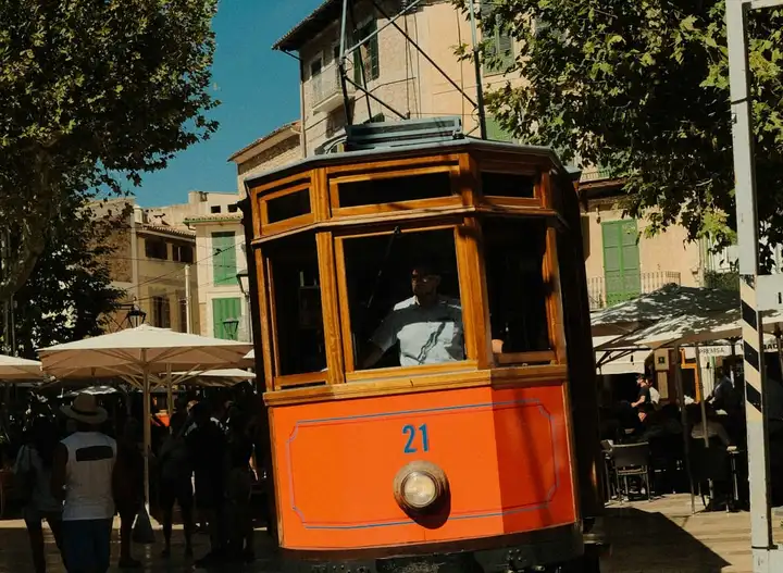 An orange tram on a tree-lined city street