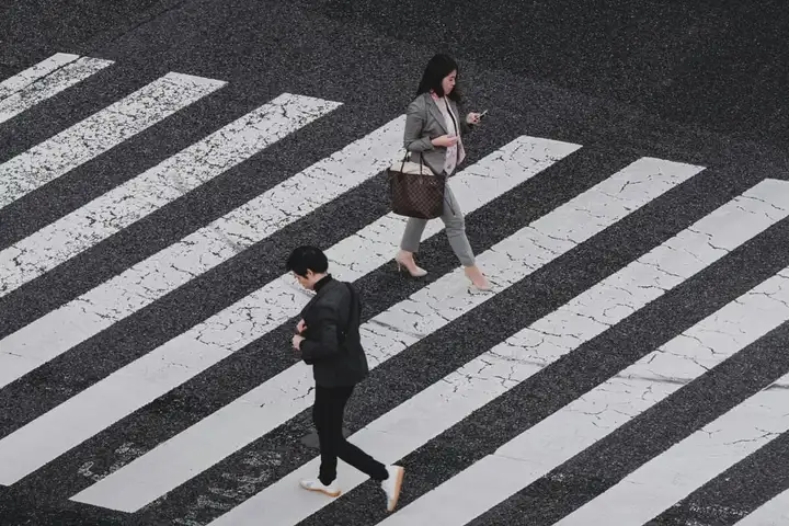 Pedestrians crossing broad white stripes on a city street