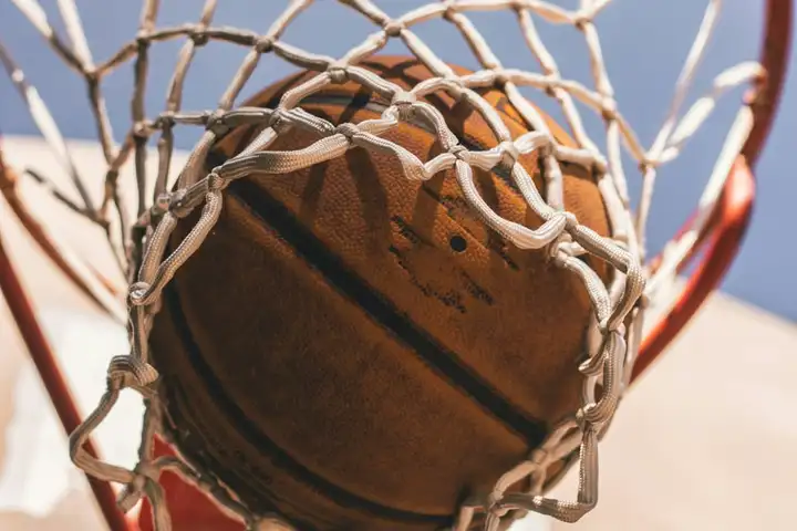 A basketball passing through an outdoor hoop