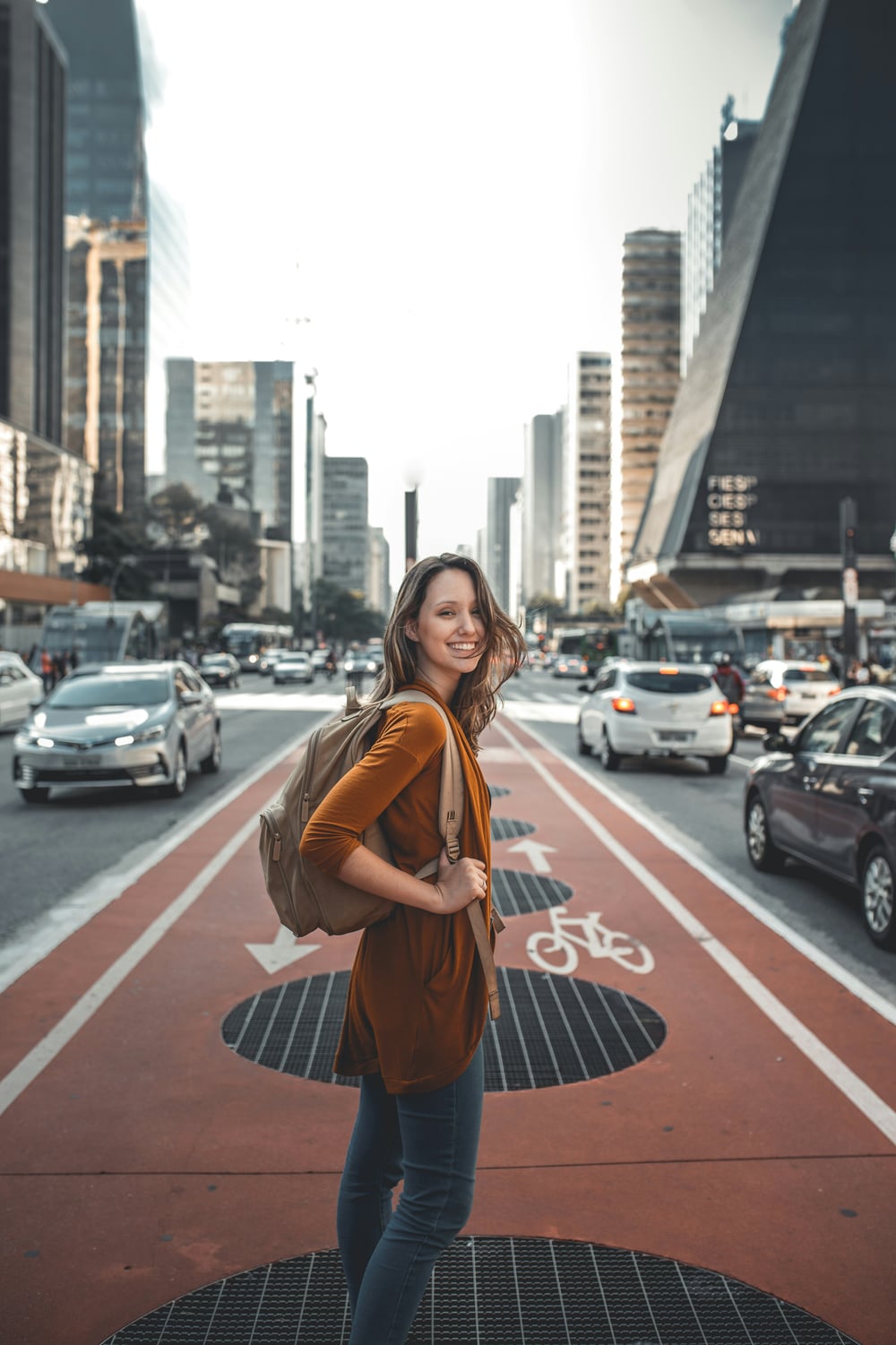 A woman turning toward the camera on a busy city avenue