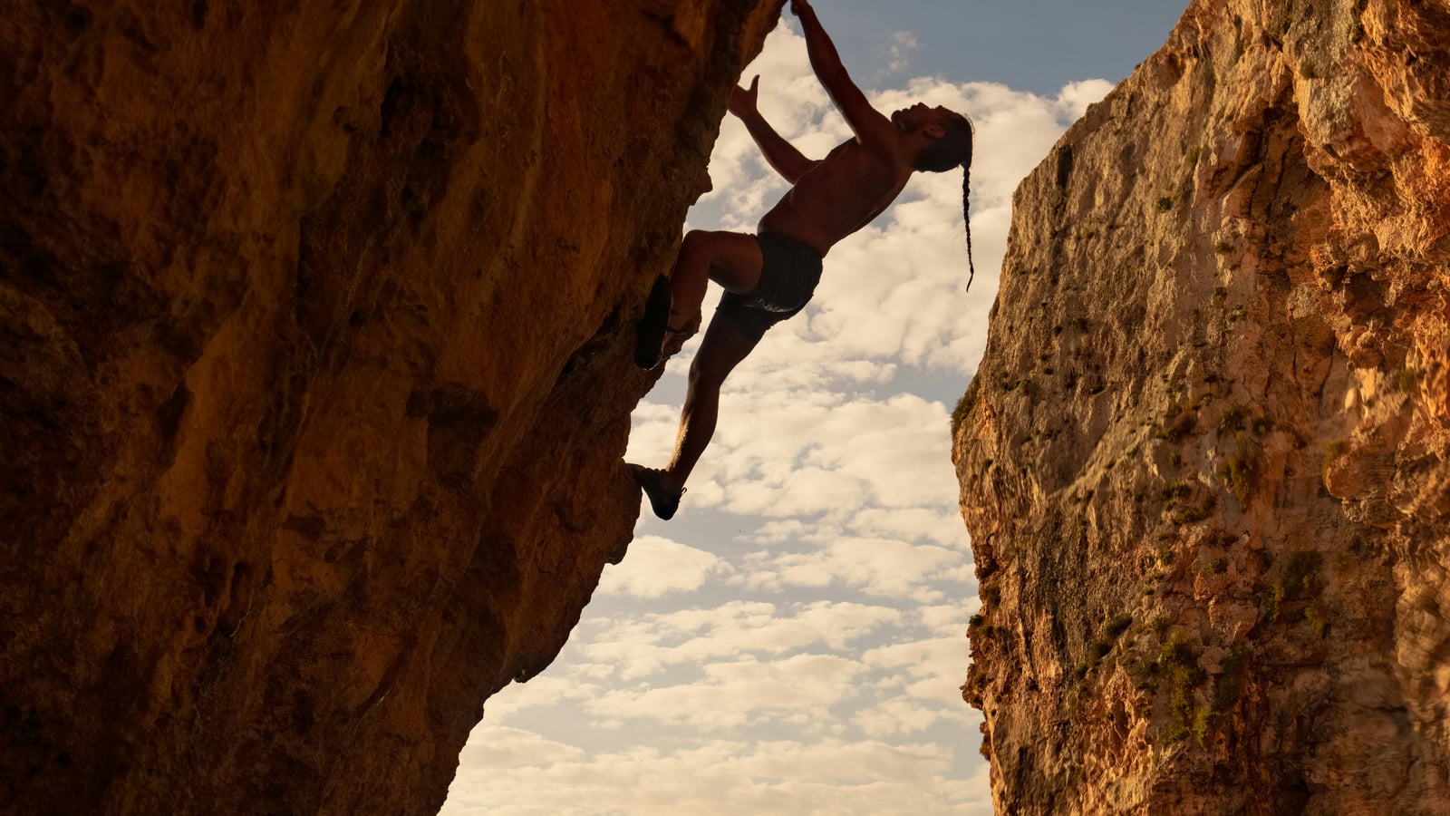 A climber silhouetted against the sky between two rock faces