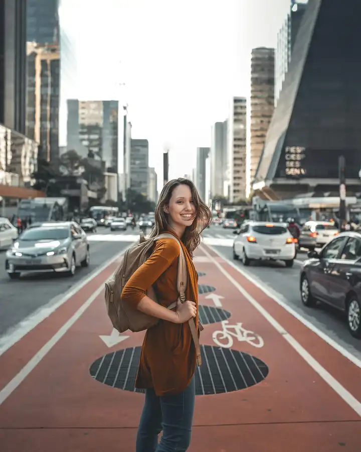 A woman turning toward the camera on a busy city avenue
