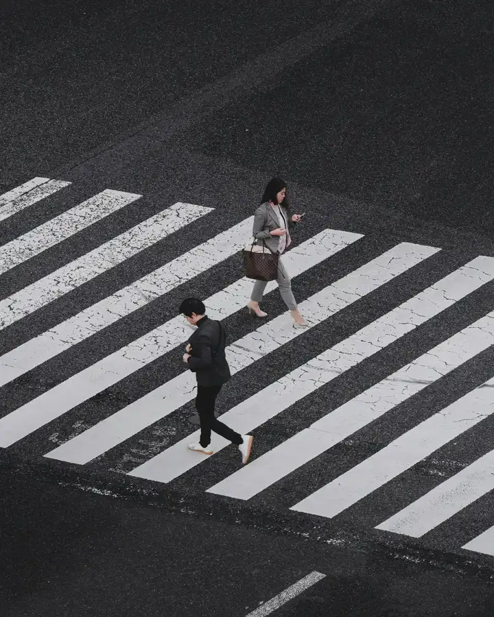 Pedestrians crossing broad white stripes on a city street
