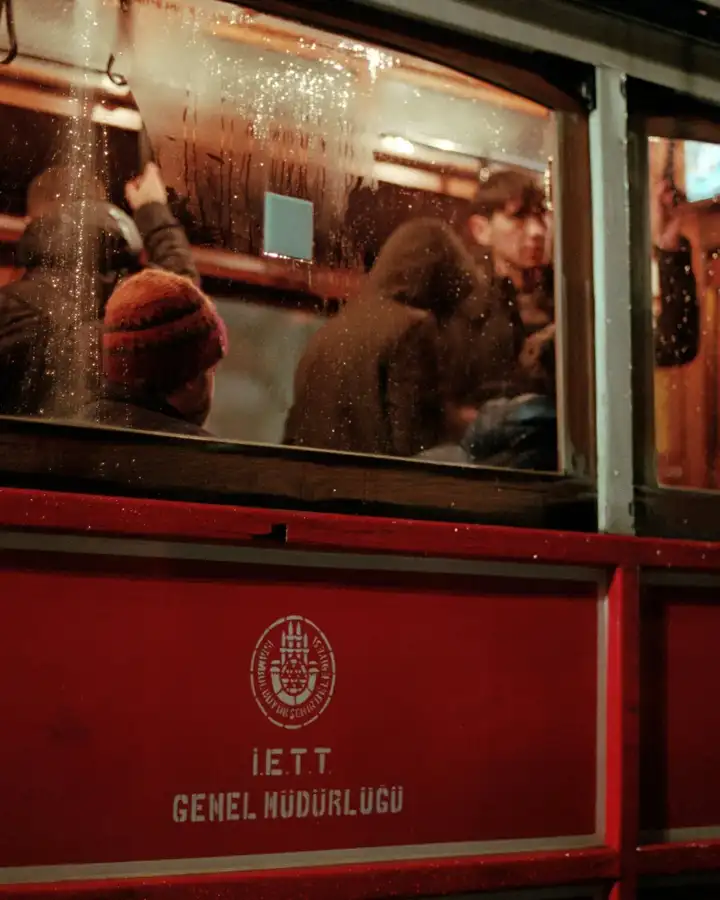 Passengers inside a warmly lit red tram at night