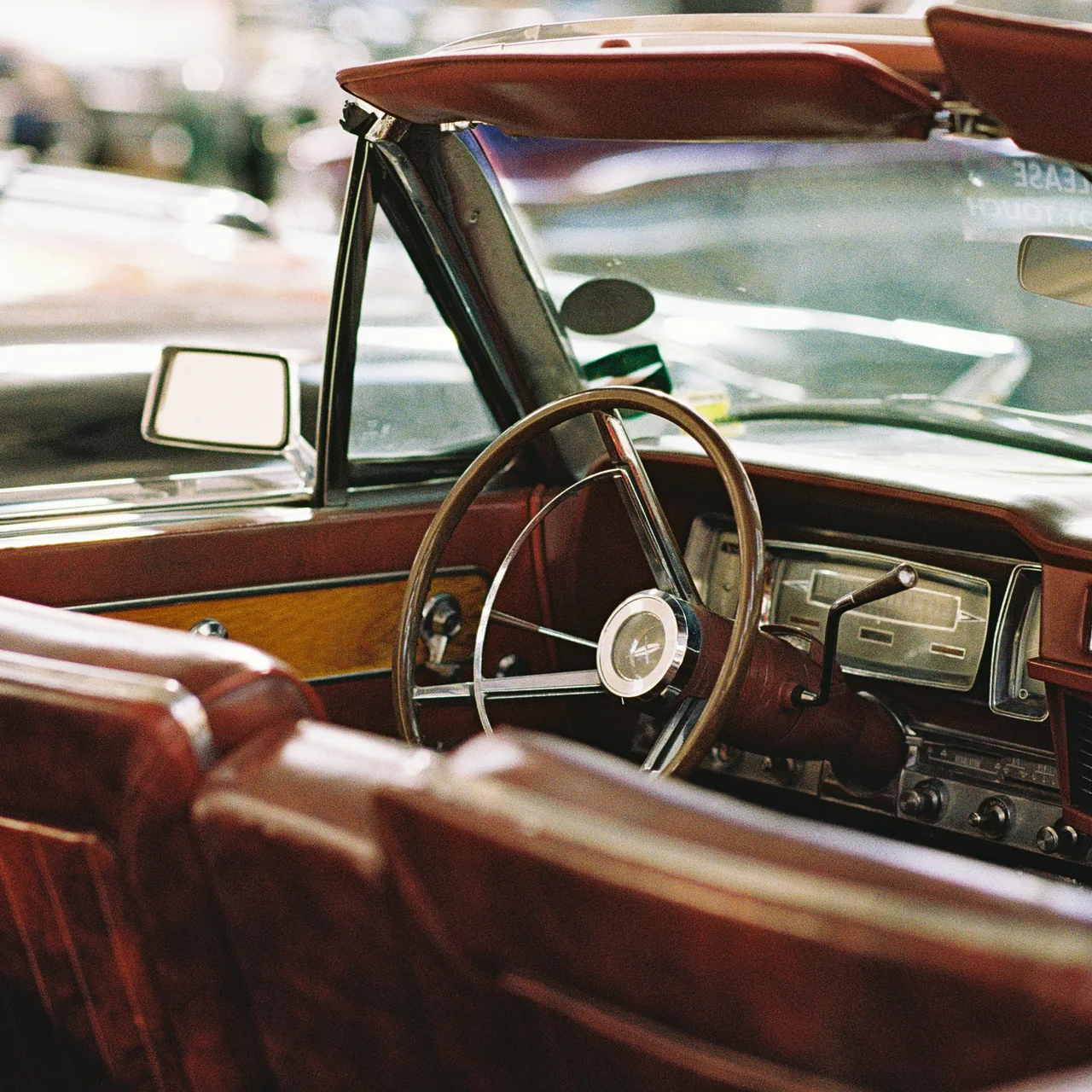 Brown leather seats and a wooden steering wheel inside a vintage convertible