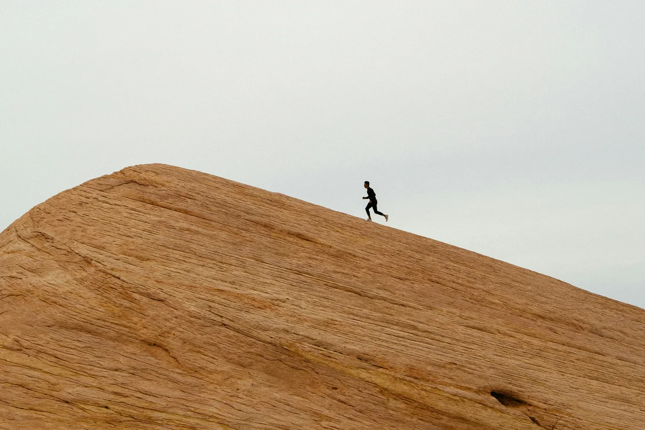 A lone figure walking along the crest of a sand dune