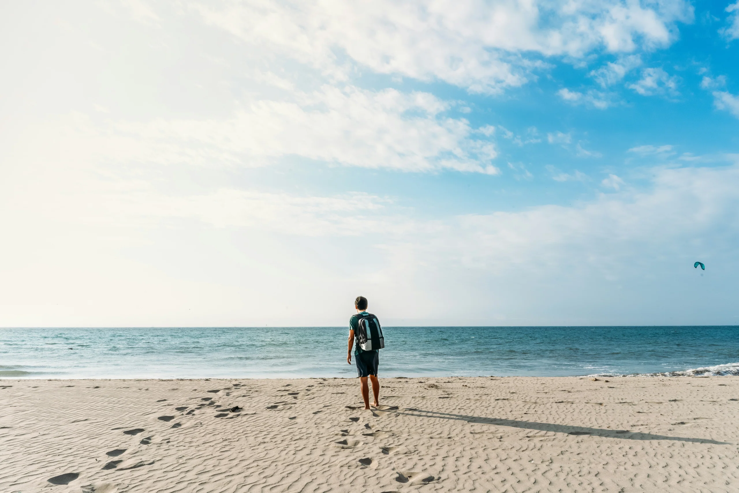 Person walking alone along a wide sandy beach