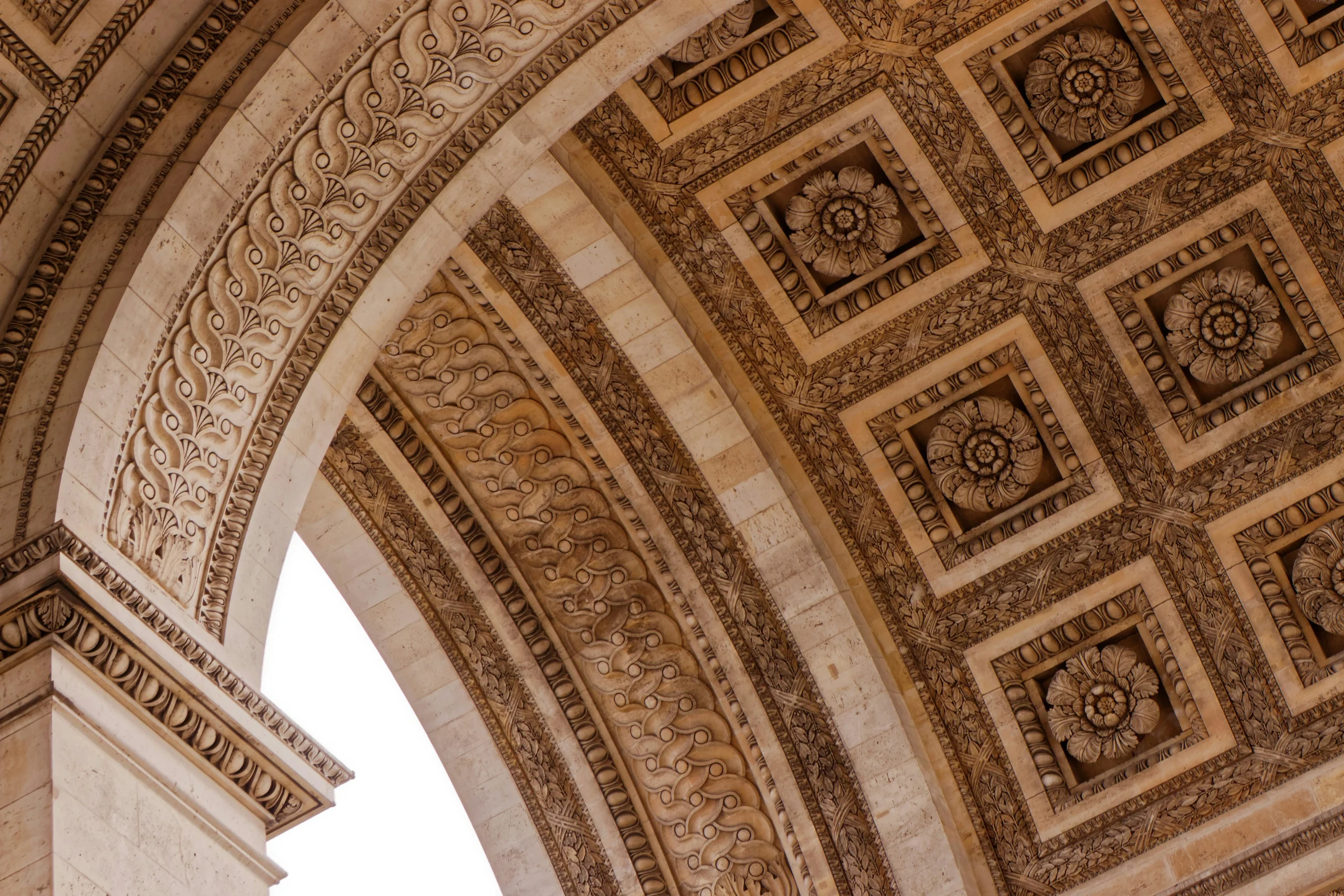 Looking up into an ornate stone arch and its coffered ceiling