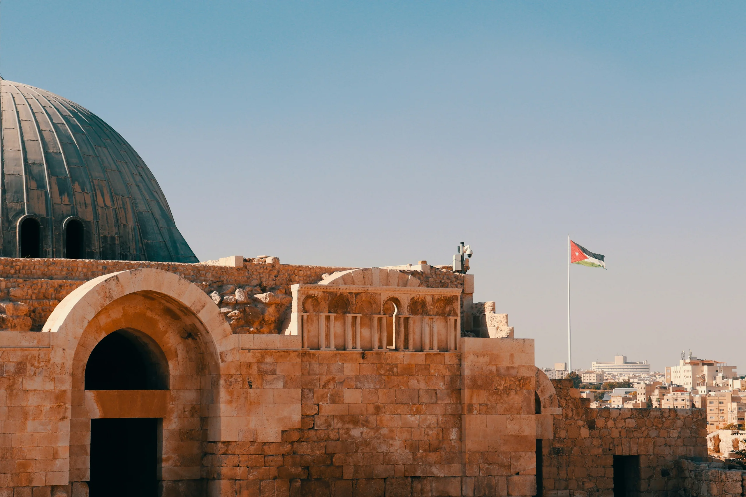 Old city of domes and a minaret under a hazy sky, a flag on the rooftop
