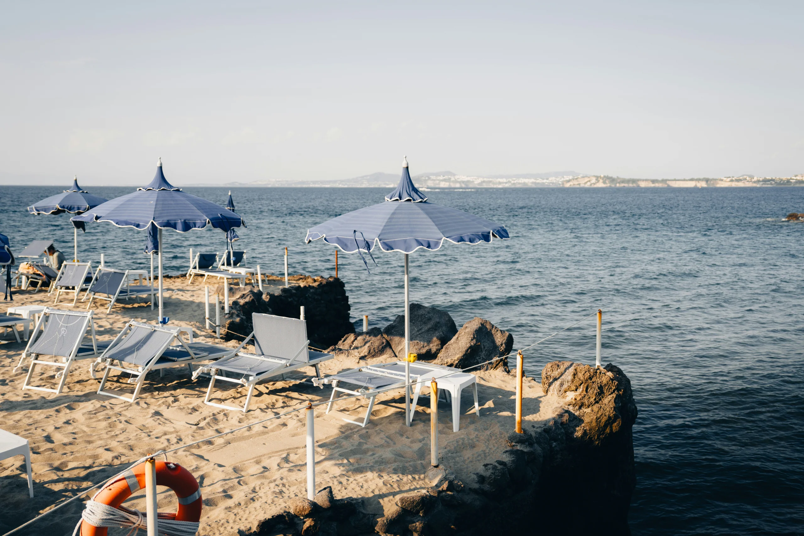 Mediterranean seaside town with beach umbrellas and boats along a blue bay