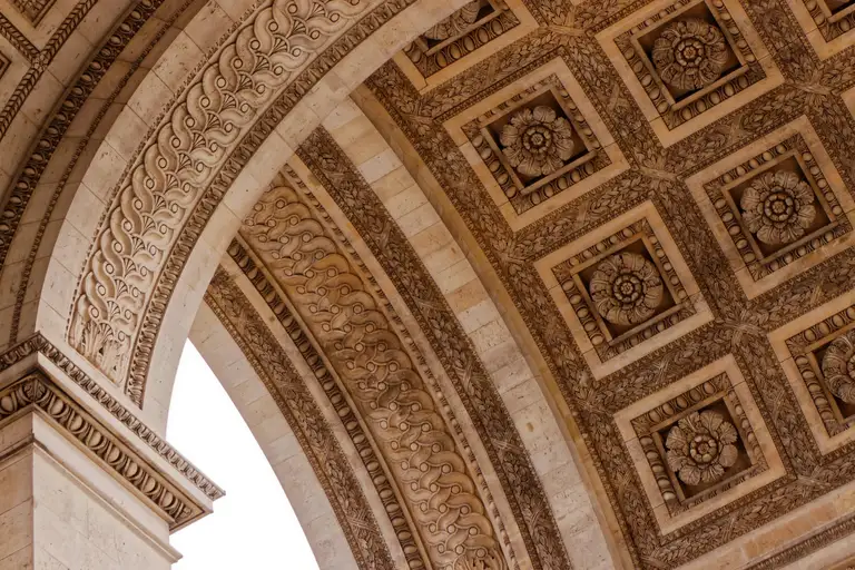 Looking up into an ornate stone arch and its coffered ceiling