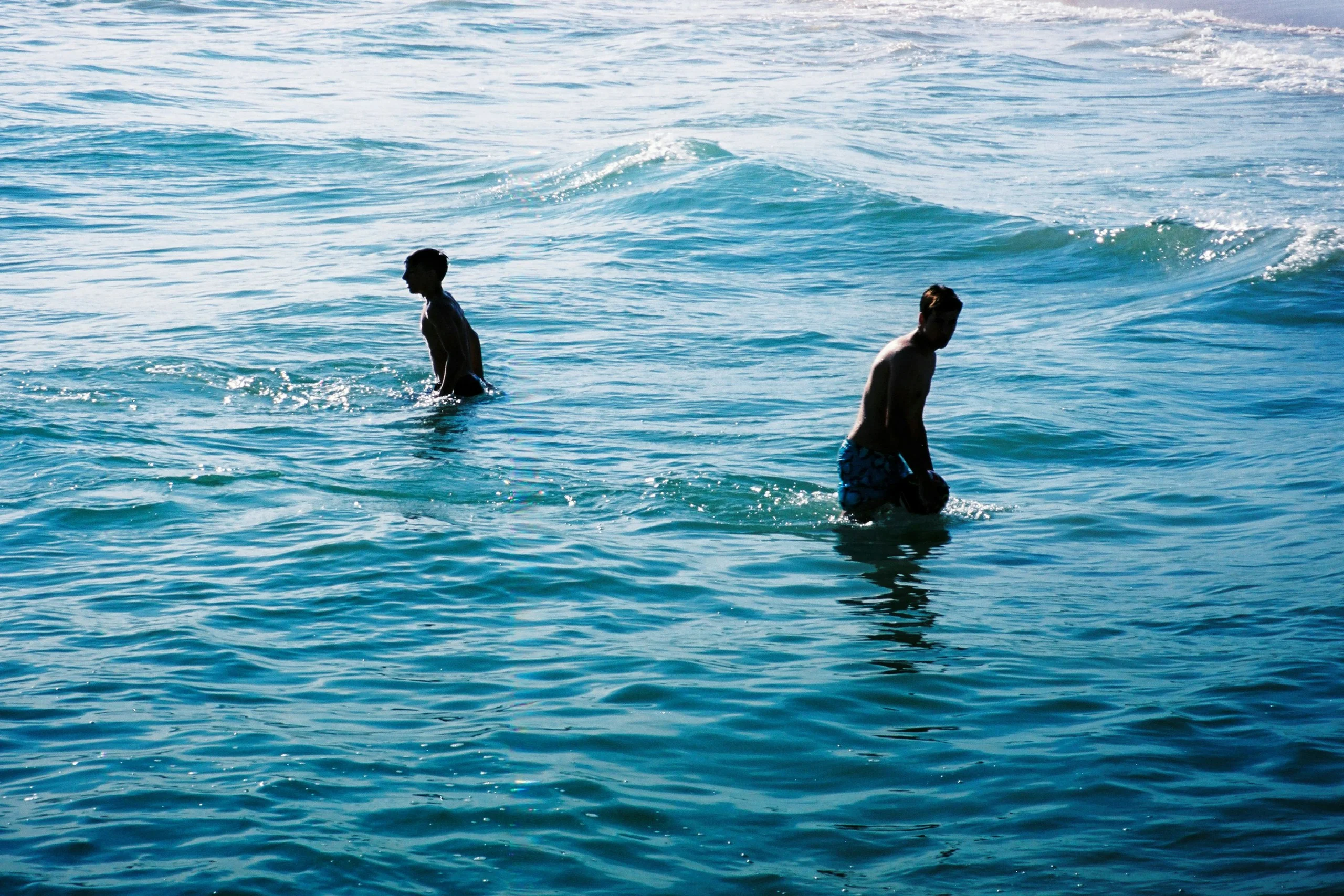 Two swimmers waist-deep in turquoise surf