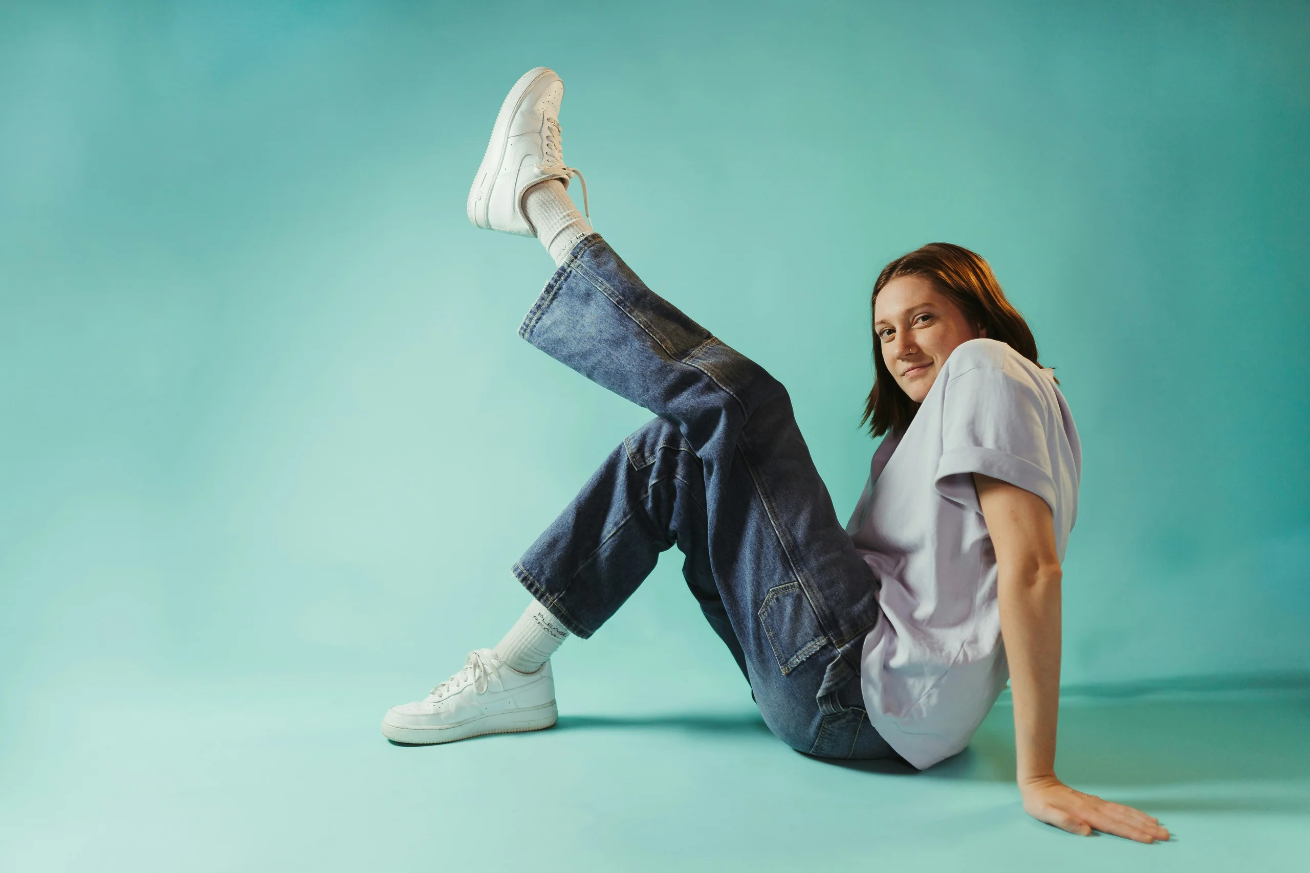 Dancer mid-kick against a teal wall